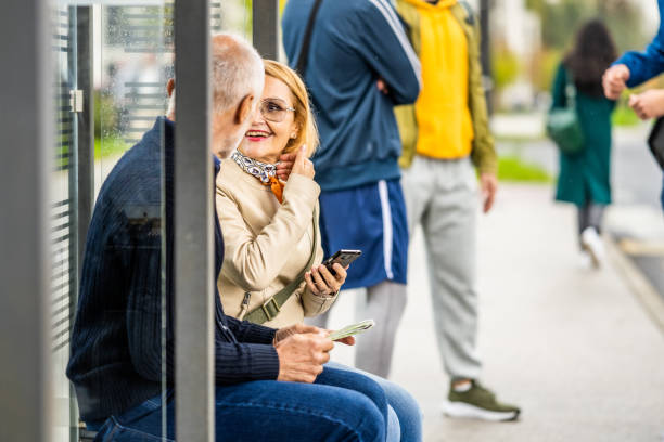 istock Senior couple sitting ar bus stop and talking, side view 1458349543