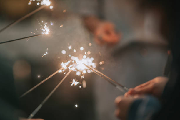 close up human hand lighting up sparklers at night Glittering burning sparkler against blurred  background