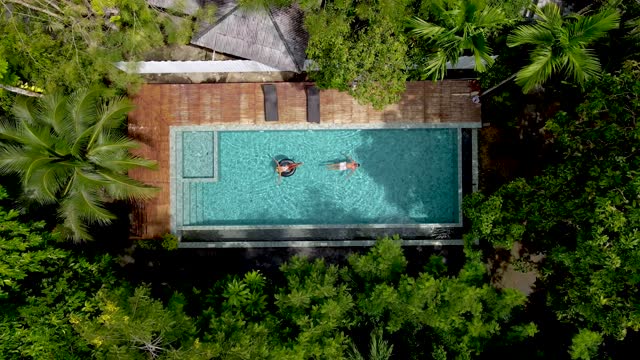 drone view from above at couple in swimming pool in the rainforest jungle