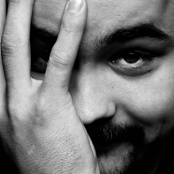 istock young man smiling, covering half of face with his hand 145835853