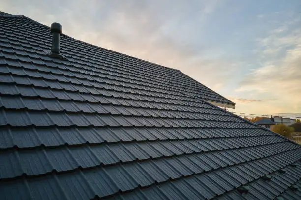 Photo of Closeup of house roof top covered with ceramic shingles. Tiled covering of building