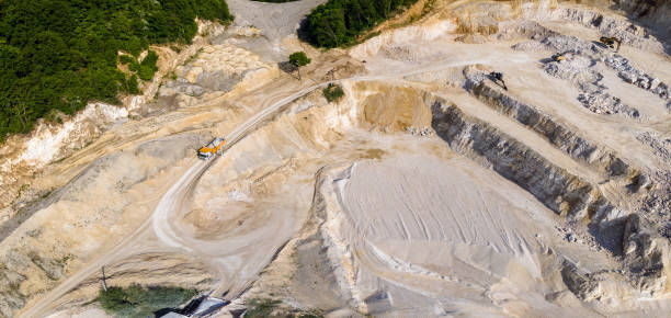 istock Open pit mining of construction sand stone materials with excavators and dump trucks. 1458359645