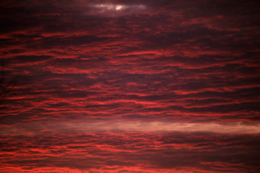 Bright colorful sunset sky with vivid smooth clouds illuminated with setting sun light spreading to horizon.