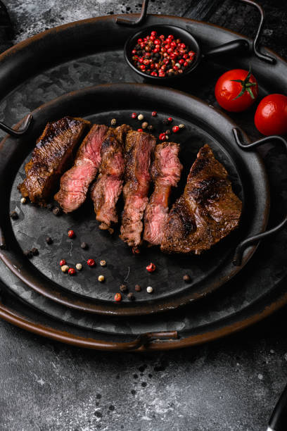 istock Sliced grilled beef barbecue Striploin steak, on black dark stone table background 1458359879