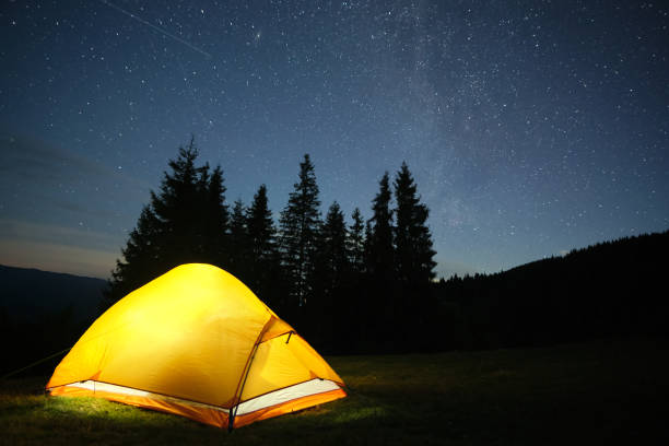istock Bright illuminated tourist tent glowing on camping site in dark mountains under night sky with sparkling stars. Active lifestyle concept. 1458359904