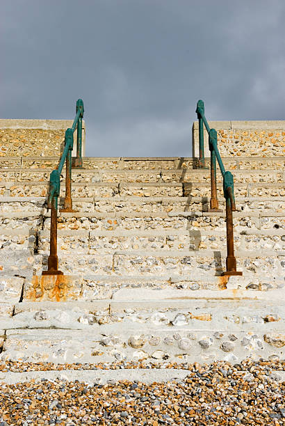 hand rail and steps leading up to a grey sky stock photo