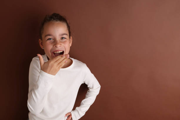 分離型茶色のチョコレートの背景に11、12歳の白い10代の少女。子供のスタジオのポートレート。テキストを配置します, 碑文用のスペースをコピーする, 子供用品を宣伝する. - 10 11 years child human face female ストックフォトと画像