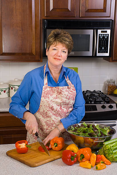 Woman in Kitchen Slicing Peppers stock photo