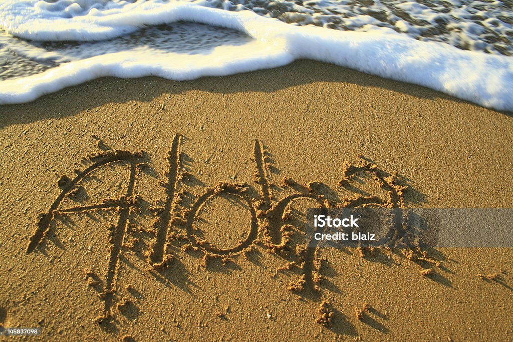 Aloha in the sand Aloha, the hawaiian term for hello, goodbye, and love, written in the sand just before being washed away by the oncomming tide. Aloha - Single Word Stock Photo