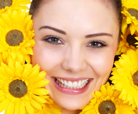 Close-up of a cheerful young woman surrounded by yellow flowers