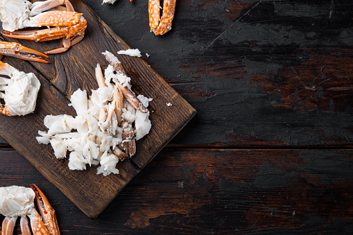 Thai blue swimming crab boiled meat parts set, on wooden cutting board, on dark wooden background, top view flat lay , with copyspace  and space for text