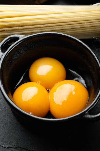 istock Bright yellow egg yolks, on black stone background 1458377068