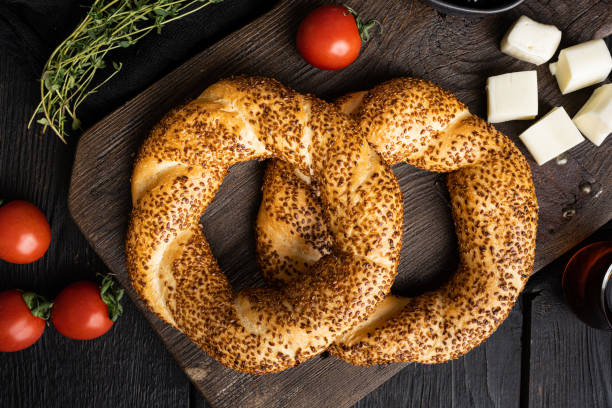 istock Turkish bagel Simit with sesame with breakfast ingredients olive and tomato cheese, on black wooden table background, top view flat lay 1458382911