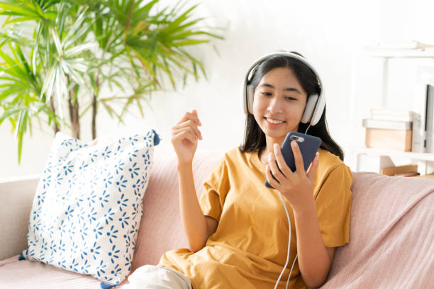 Asian woman listening to music on smartphone with headset enjoy. stock photo