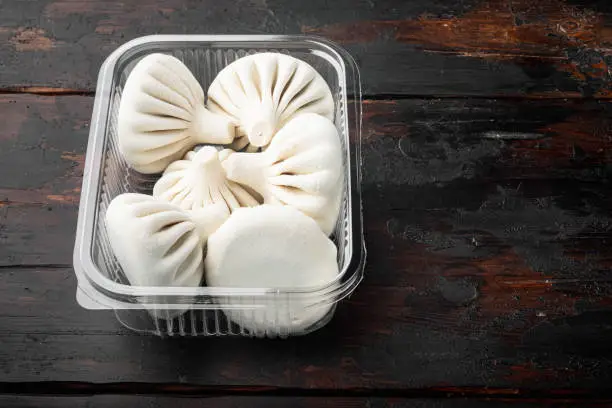 Photo of Uzbek Manti. Manti or manty dumplings, popular uzbek-asian dish, in plastic tray, on old dark  wooden table background, with copy space for text