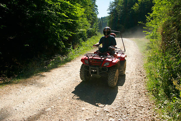 istock Person riding a red ATV down a dirt lane in a helmet 145839049