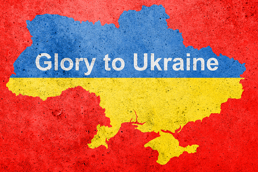 Flag of Ukraine painted on a concrete wall with inscription GLORY to Ukraine .