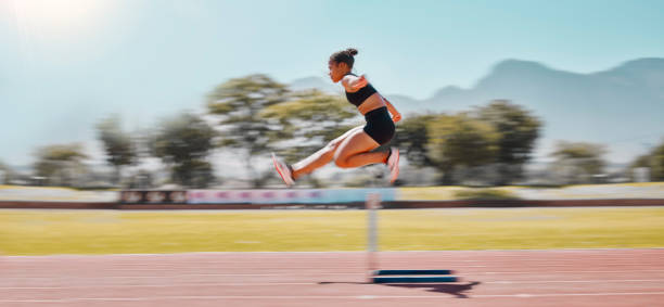 athlète, sport et saut féminin haies pour l’épreuve d’athlétisme pour la course d’obstacles ou course pour la course, l’exercice et l’entraînement pour le marathon. outdoor féminin pour le sport, l’entraînement et l’énergie dans un st - marathon running motion track event photos et images de collection