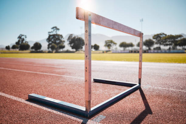 empty stadium, field and running hurdle or barrier at outdoors race track. sports, athletics or jumping obstacle, metal equipment for runners or athletes for competition, exercise or training outside - hurdle conquering adversity obstacle course nobody imagens e fotografias de stock