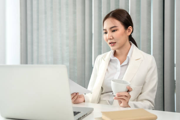 istock Professional businesswoman analyzing graph data from document in hand, Market research reports and income statistics, Woman working in a private office, Financial and Accounting concept 1458400855