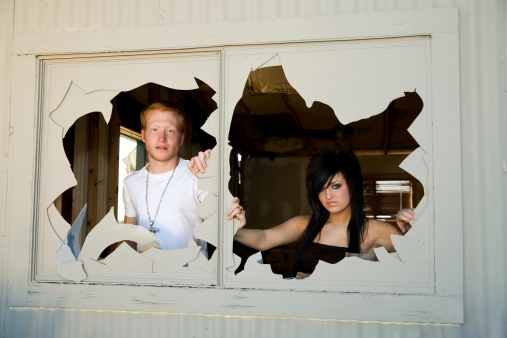 a young couple looking out of broken windows