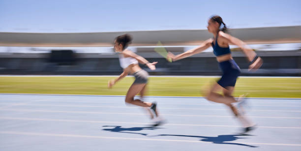 Relay race, running and sports women at a stadium for training, energy and workout. Sport, runner and baton pass on a running track by athletic team for fitness, marathon and speed performance Relay race, running and sports women at a stadium for training, energy and workout. Sport, runner and baton pass on a running track by athletic team for fitness, marathon and speed performance passing sport stock pictures, royalty-free photos & images