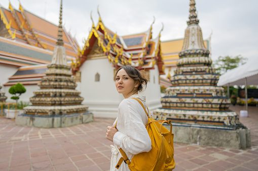 Young Caucasian woman in white dress  exploring  Wat Pho in Bangkok