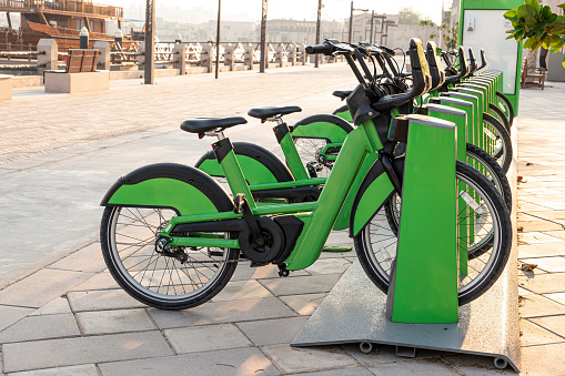 electric bicycles for rent are green in the parking lot in the city center on the street. Eco-friendly mode of transport