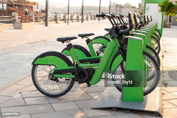 Electric Bicycles For Rent Are Green In Parking Lot In The City Center On The Street Ecofriendly Mode Of Transport Stock Photo - Download Image Now