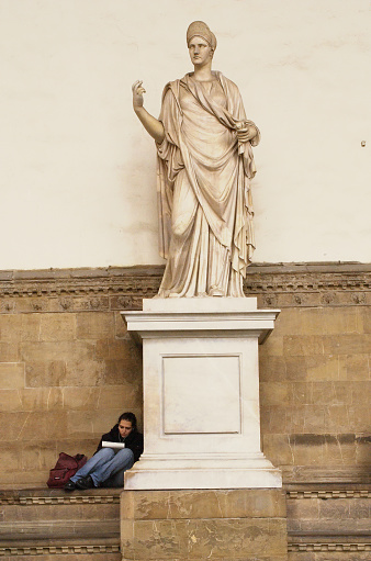 A girl reads a book sitting by an ancient sculpture in Florence, Italy, 13 november 2008