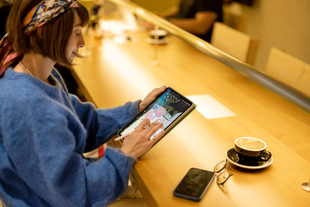 istock Woman works on touchpad at coffee shop 1458420130