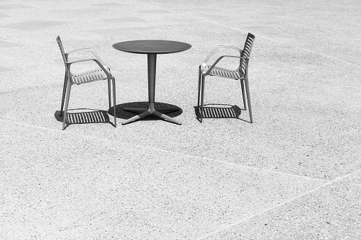 Black and white photo of two chairs at an empty table, space for text.