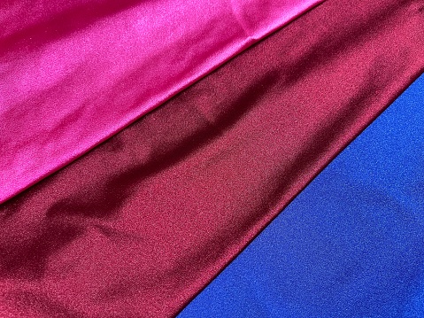 Background of maroon, pink and blue shiny fabric flat surface with copy space for fashion design