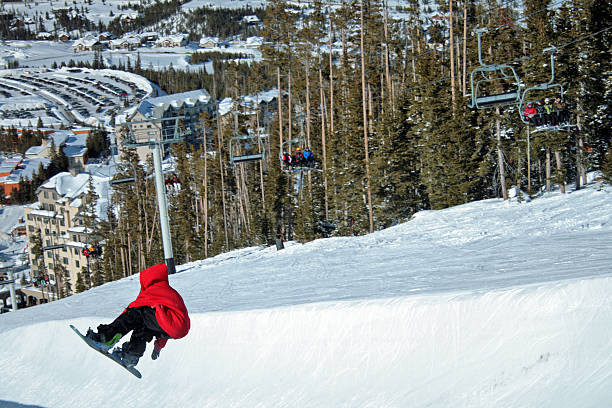 Snowboarders in halfpipe A young man takes flight in the halfpipe at Big Sky, MT while spectators observe from a chairlift. big sky ski resort stock pictures, royalty-free photos & images