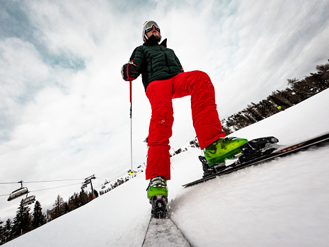 Young male skiing in the austrian alps on a groomed ski slope. Point of view camera, mounted on the skis, cloudy day.