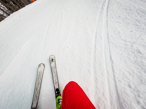 Young male skiing in the austrian alps on a groomed ski slope. Point of view camera, mounted on the skis, cloudy day.