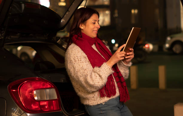 istock Young woman using digital tablet standing with her car at night 1458423815