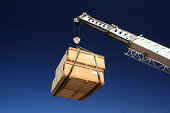 Two wooden crates hanging from a crane lift 