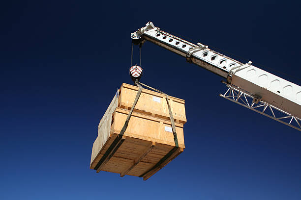 Two wooden crates hanging from a crane lift Two wooden crates hanging from a crate. transport construction machineries stock pictures, royalty-free photos & images