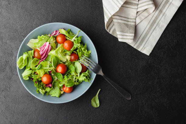 istock Green salad leaves in bowl on black table. 1458425592