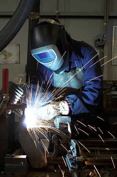 Welder welding a car chassis in an industrial environment