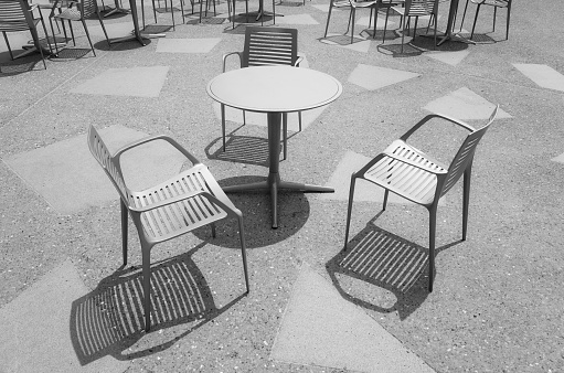 Black and white photo of chairs at an empty table.