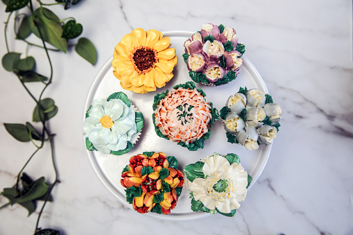 Various cupcakes decorated with colorful flower icing on white cupcake stand and table for party, floral bouquet, wedding cake, High tea, Holiday concept beauty