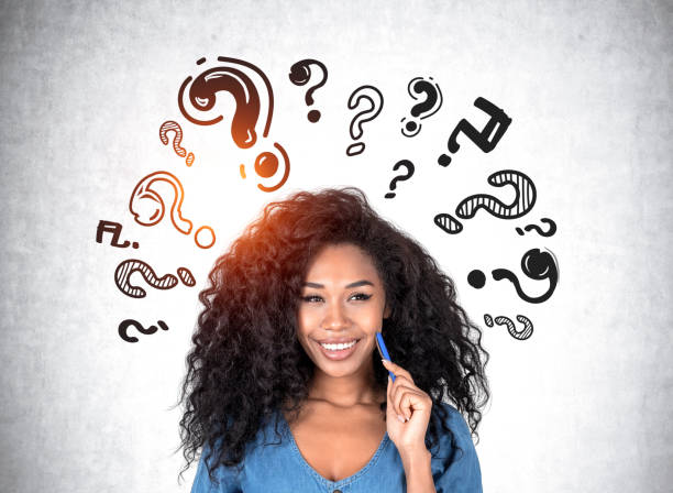 istock African woman with a dreaming look, question marks on grey wall 1458434552