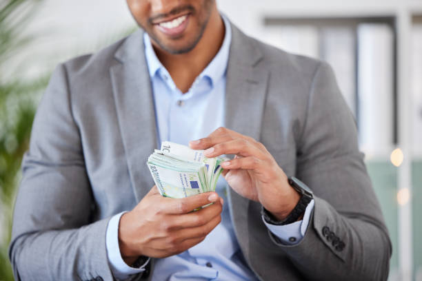 Hands, money and finance with a business man counting cash while accounting or banking in his office. Financial, investment and loan with a male employee working as an economy accountant for profit manos, dinero y finanzas con un hombre de negocios contando efectivo mientras contable o realiza operaciones bancarias en su oficina. financiero, inversión y préstamo con un empleado masculino que trabaja como contador de economía con fines de lucro