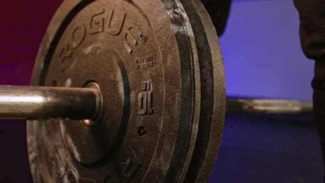 Hands adding weight to barbell rod at gym