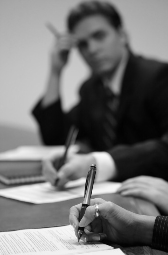 three people at boardroom signing documents