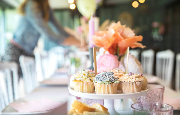 frische cupcakes mit schlagsahne und devorativer blumenglasur serviert auf einem teller auf partytisch, hochzeit, babyparty, high tea, geburtstagsurlaub - party tea party tea child stock-fotos und bilder