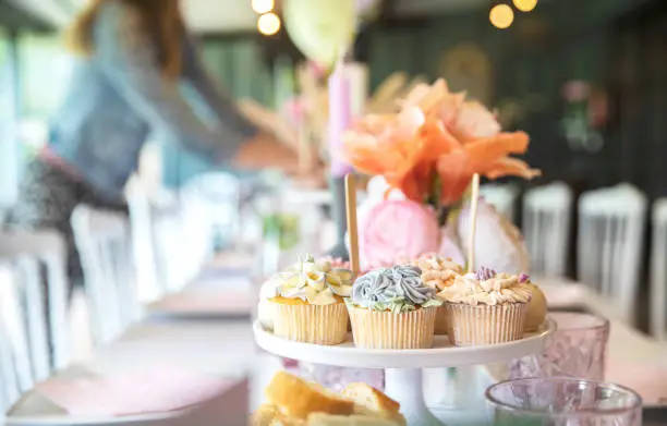 Photo of Fresh cupcakes with whipped cream and devorative flower icing served on a plate on party table, wedding,baby shower,high tea, Birthday holiday