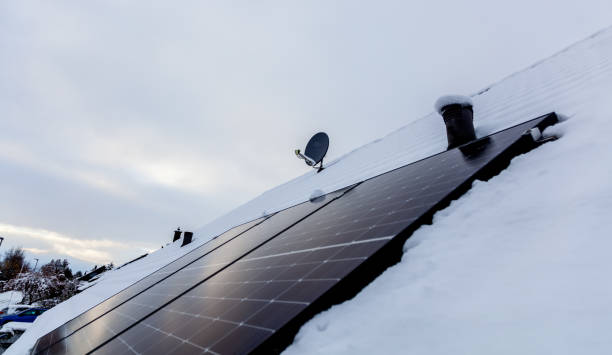 istock panel at rooftop with snow. removing snow off solar panels in winter. Removing snow photovoltaic system - solar cells. snow covers panels - no producing power. energy efficiency 1458444410